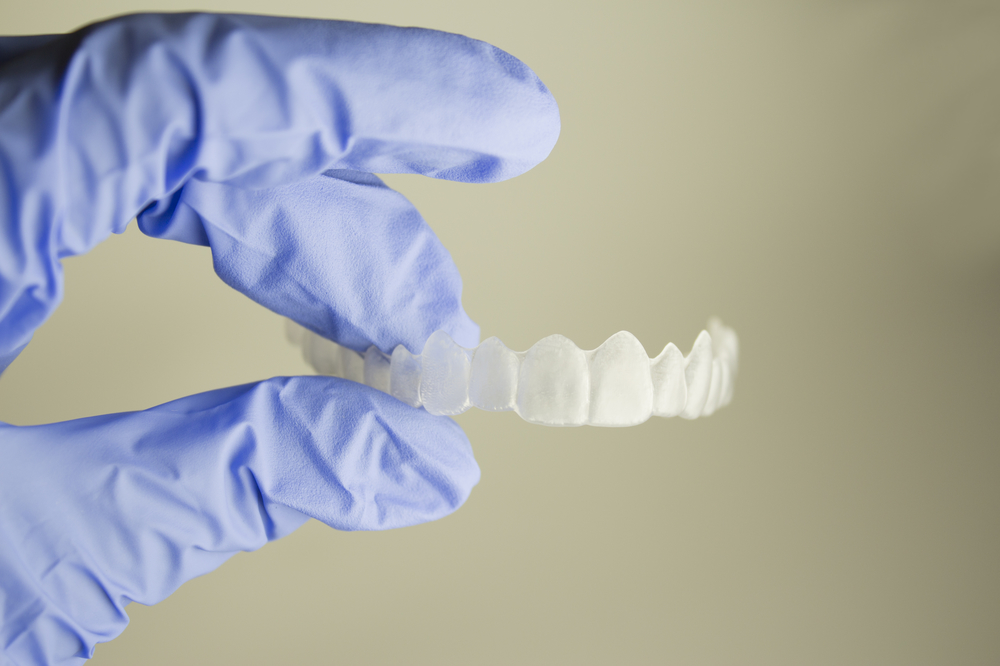 Dentist hand holding invisalign clear aligners.