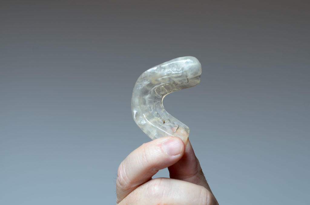Hand holding a mouth guard which can aid in alleviating sleep apnea. 